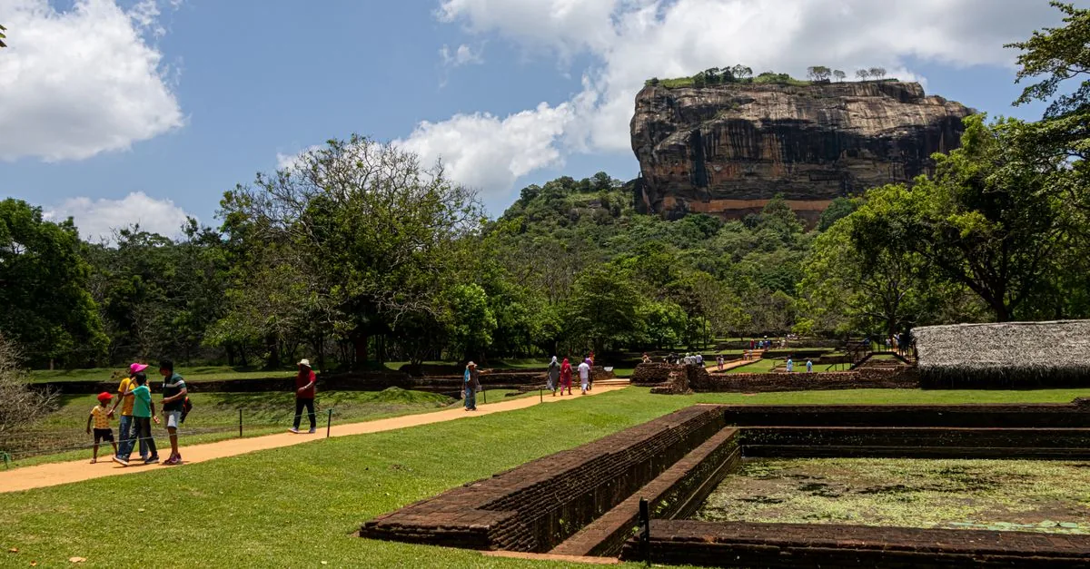 Visitors approach the Lion Rock in Sigiriya through the greenery.